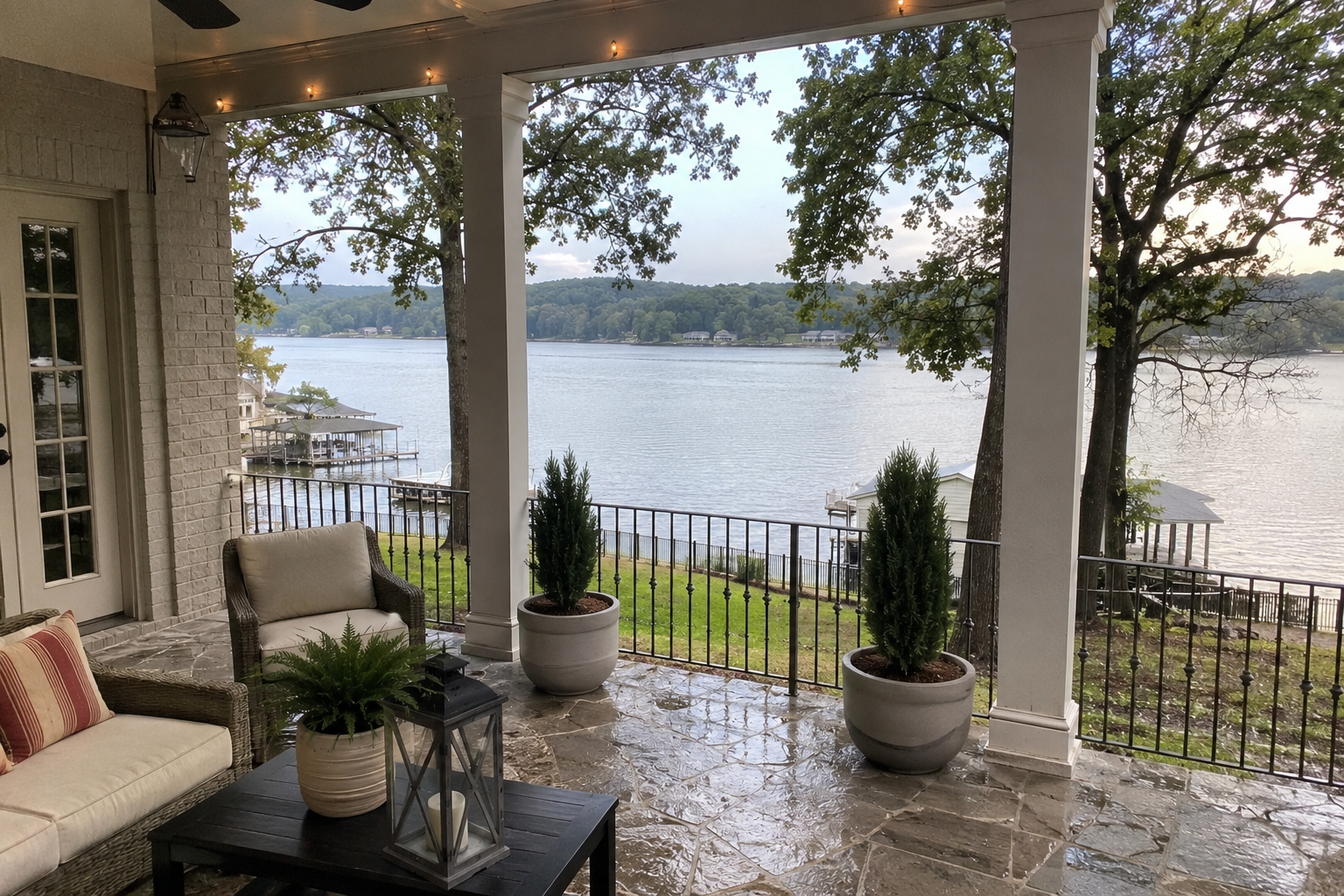 Covered outdoor living space overlooking Lake Guntersville with a stone patio, white columns, and scenic waterfront views in Guntersville, AL.