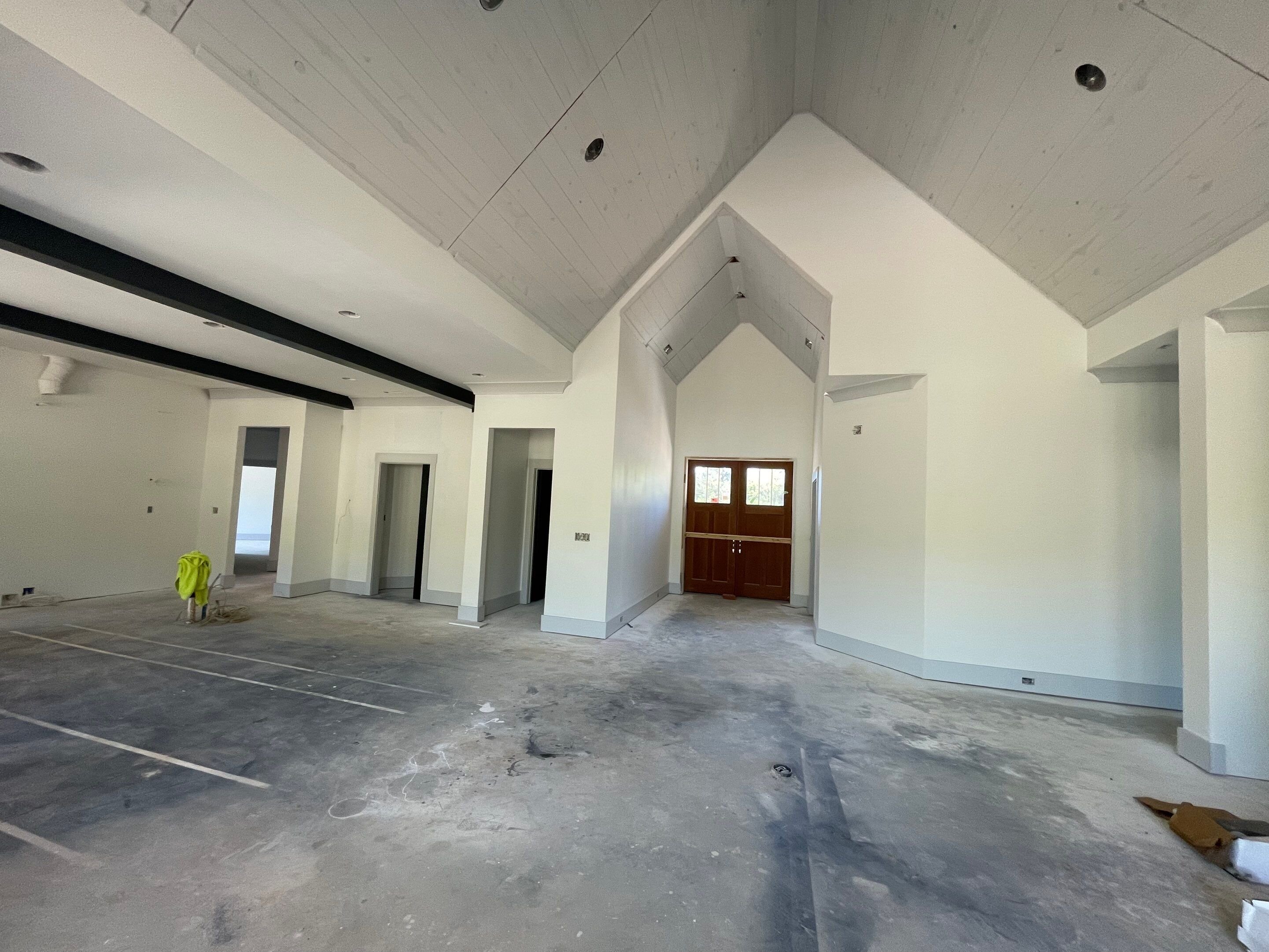 Unfinished interior construction phase of a luxury home showing vaulted ceilings, white shiplap, and custom door entryway in Hazel green, Alabama.