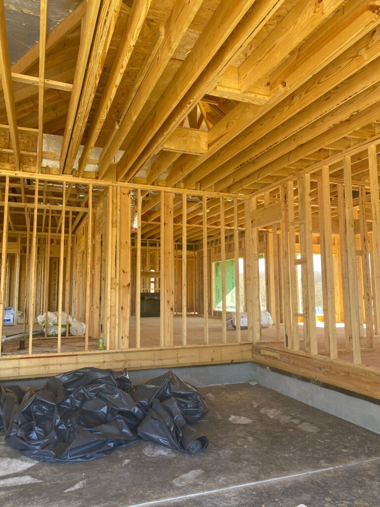 Unfinished interior construction phase of a luxury home showing vaulted ceilings, white shiplap, and custom door entryway in Hazel green, Alabama.
