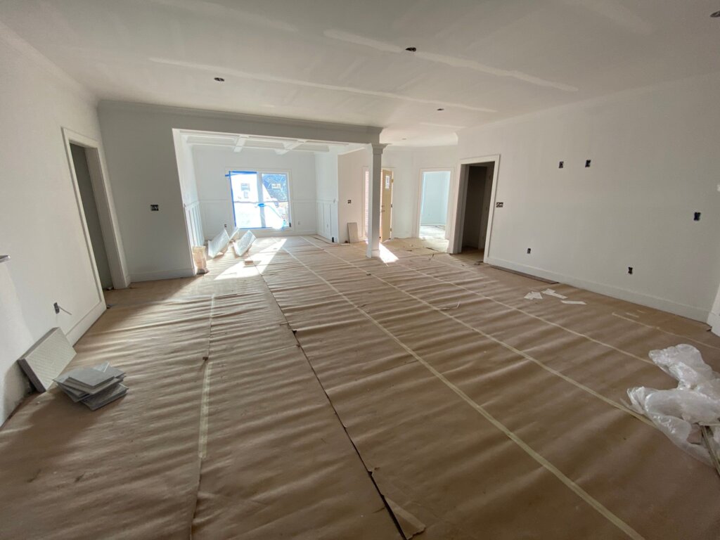 Spacious open-concept luxury custom home interior during the finishing stage with drywall, trim, and floor protection in Hazel Green, AL.