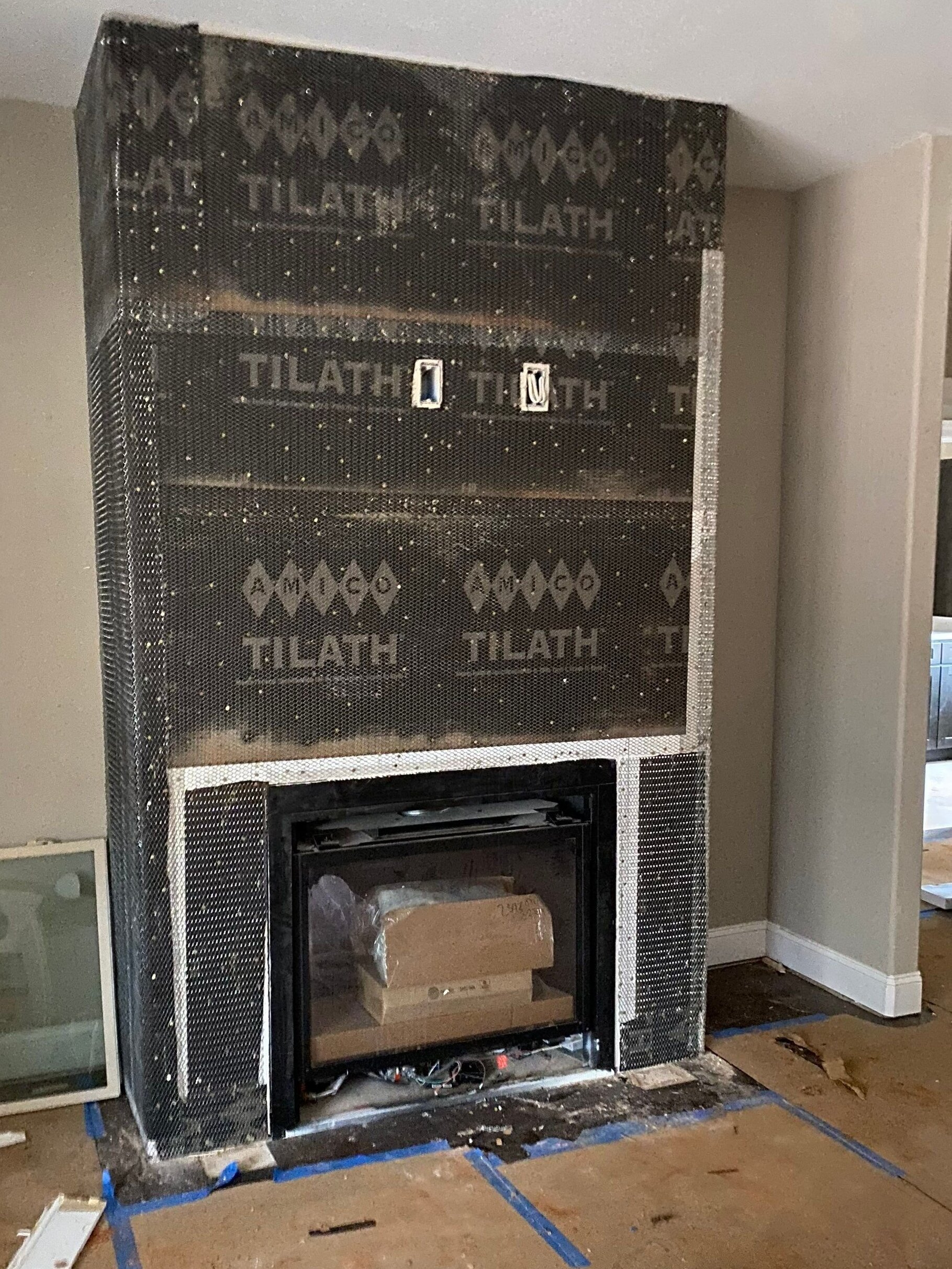 Custom fireplace installation in progress featuring a modern gas fireplace and stone veneer preparation in a luxury custom home in Hazel Green, AL.