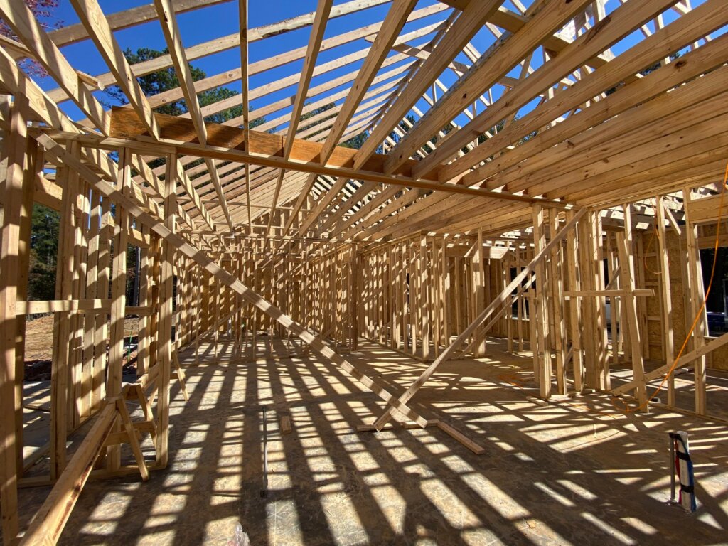 Luxury custom home framing with engineered roof trusses and open-concept floor plan under construction in New Market, AL.