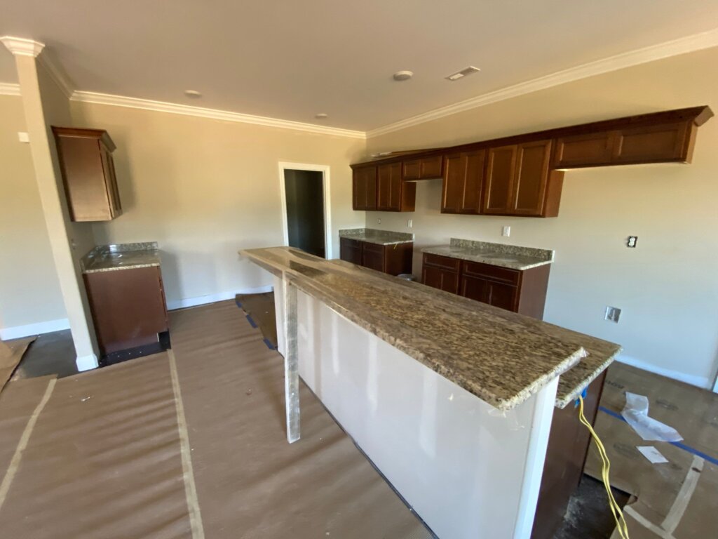 Luxury custom kitchen under construction with granite countertops, custom wood cabinetry, and a spacious island in New Market, AL.