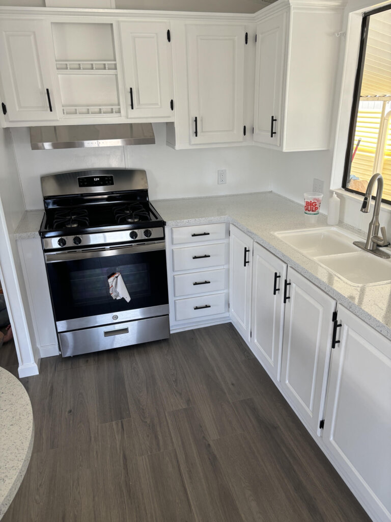 The finished kitchen after the renovation, including refreshed cabinetry, refinished countertops, and new appliances.