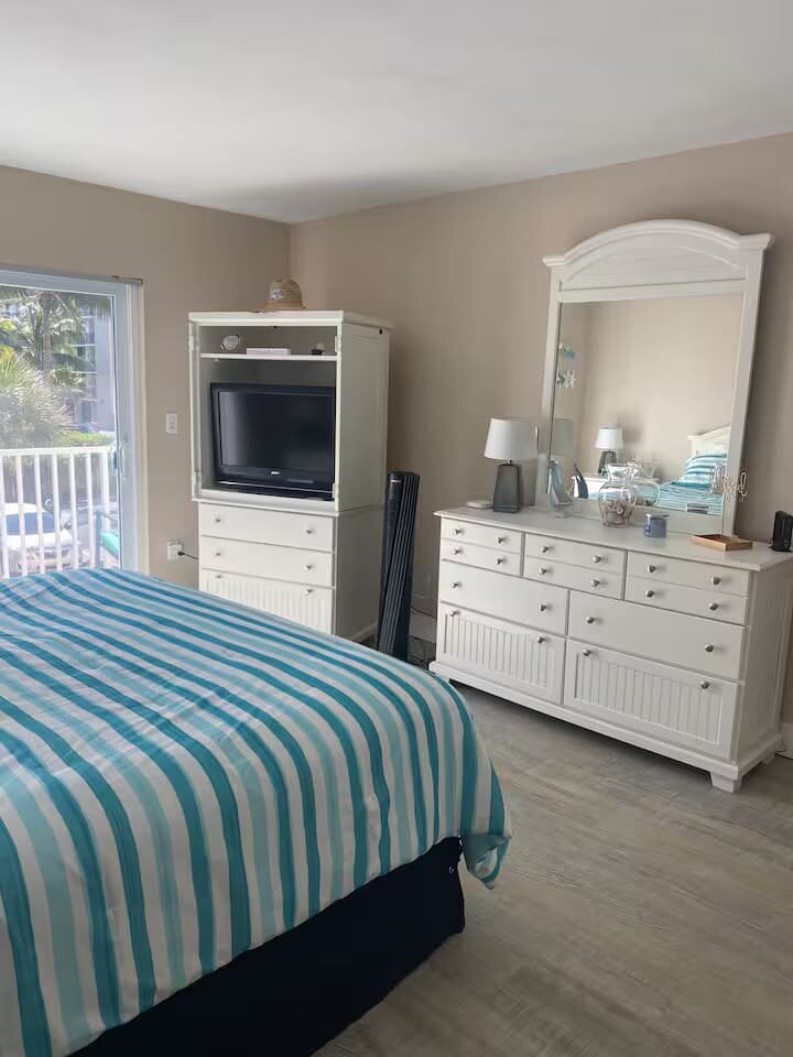 Bedroom with striped bedding and TV armoire