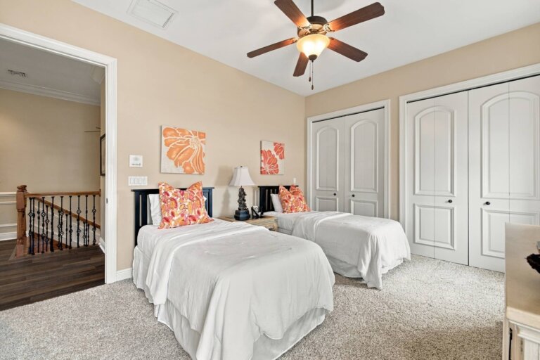 Bedroom with two twin beds, coral accents and a ceiling fan