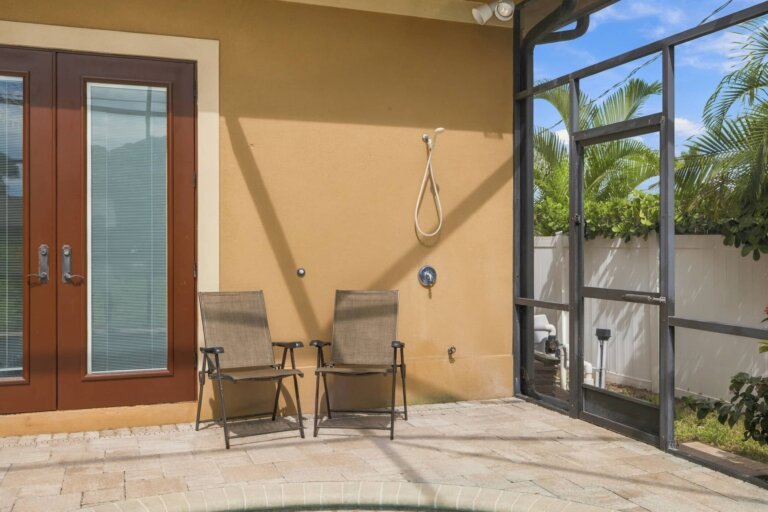 Covered lanai with two outdoor chairs beside the screened pool area