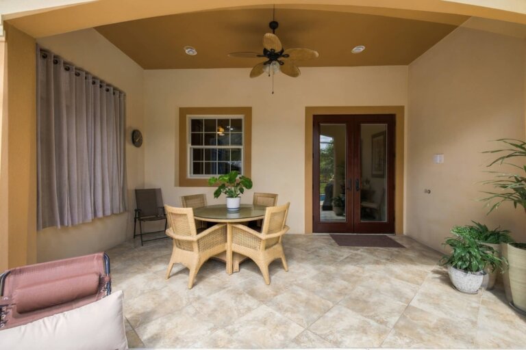 Covered outdoor dining area with a wicker table, chairs and ceiling fan