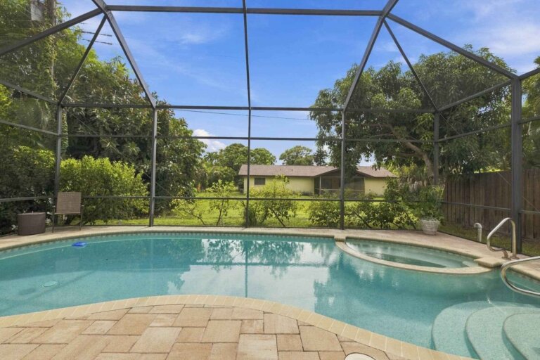 Private pool with a paver deck inside a large screened enclosure