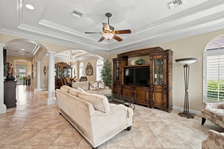 Living room with cream sofas, a wood entertainment cabinet and arched openings to the dining area
