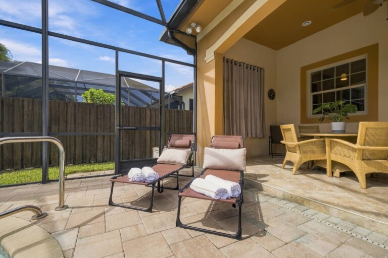 Covered lanai with two padded lounge chairs inside the screened pool enclosure