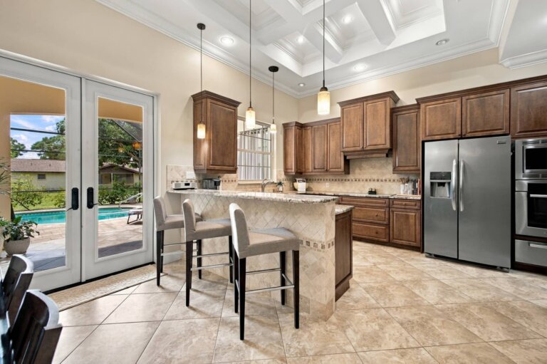 Kitchen with a granite center island, bar seating, pendant lights and rich wood cabinetry