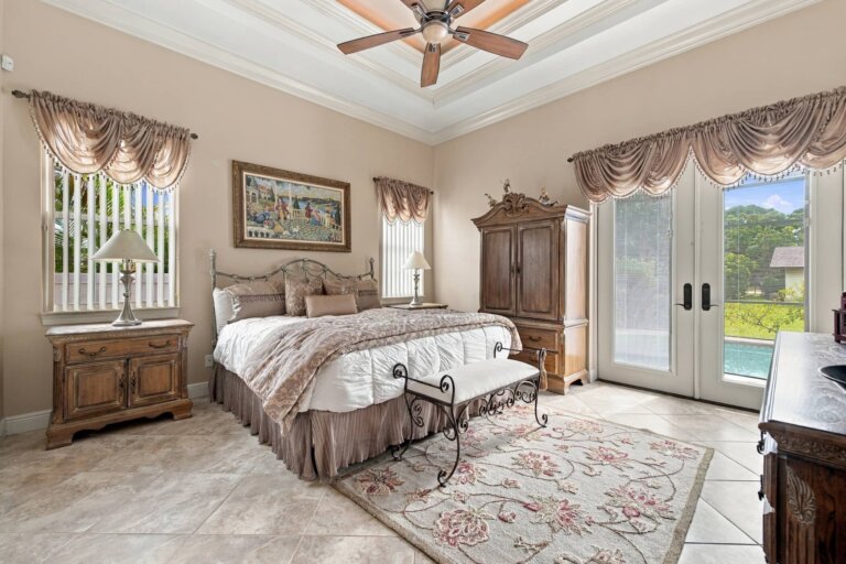 Primary suite with a king-size bed, ceiling fan and tray ceiling