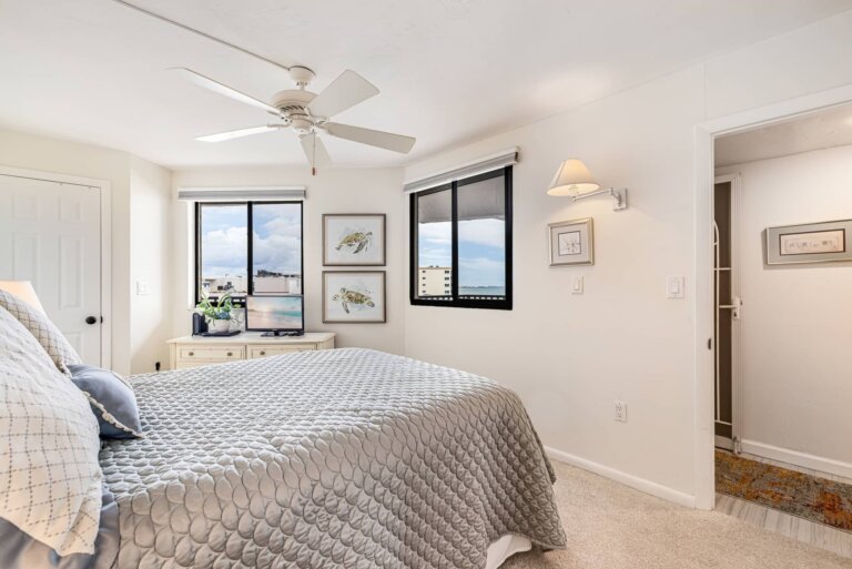 Guest bedroom with a queen bed, ceiling fan and windows