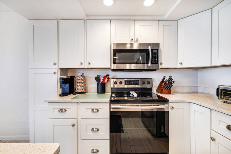 White kitchen cabinetry with an electric stove and microwave