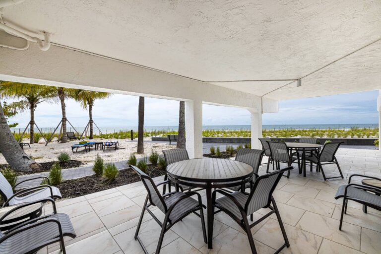 Shaded outdoor seating and dining tables near the beach