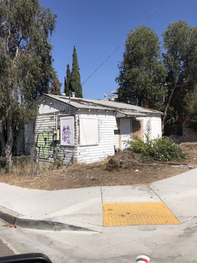 Distressed fixer-upper home with boarded windows before renovation in Southern California