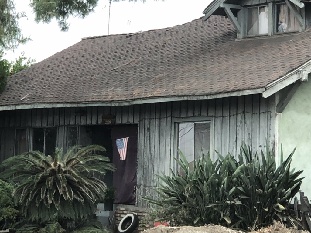 Distressed single-family home with weathered wood siding before renovation in Southern California