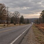 Two-lane highway corridor in north Jefferson County with ranch houses on one side and a cleared construction site on the other
