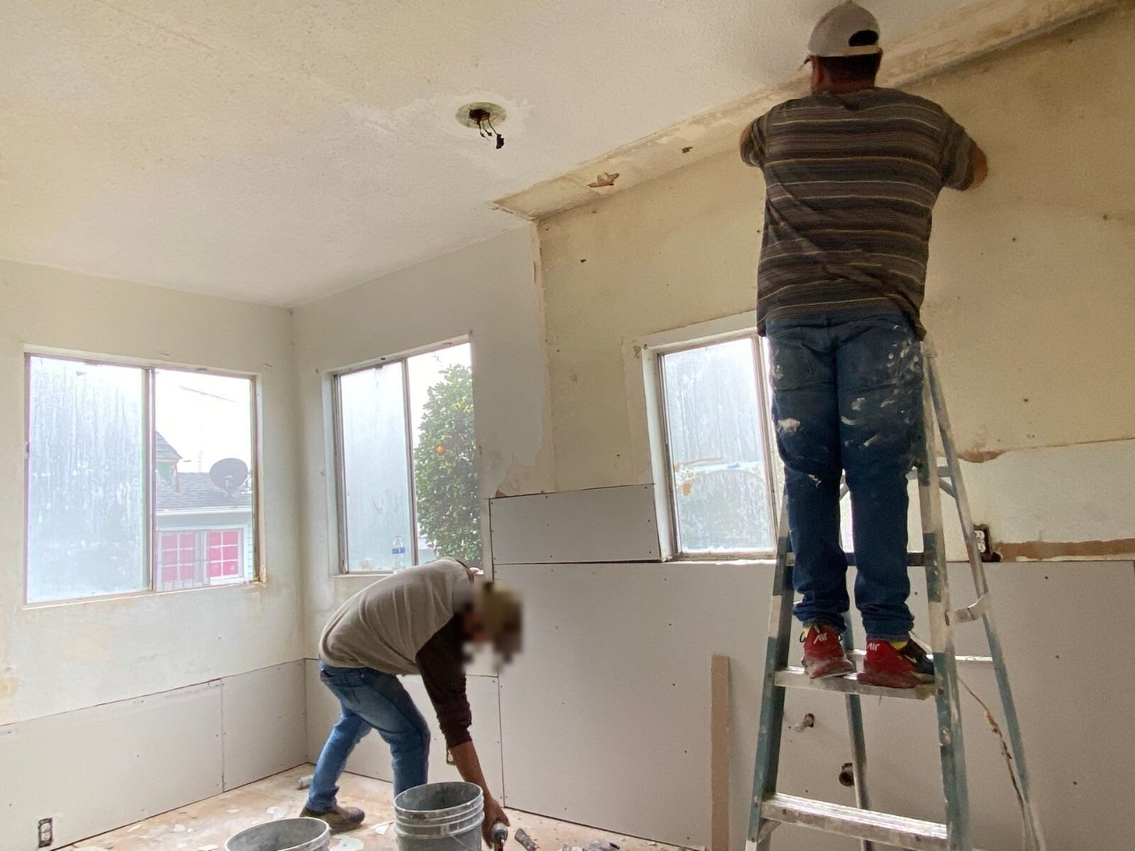 Our crew hanging new drywall in a Fresno house we bought as-is