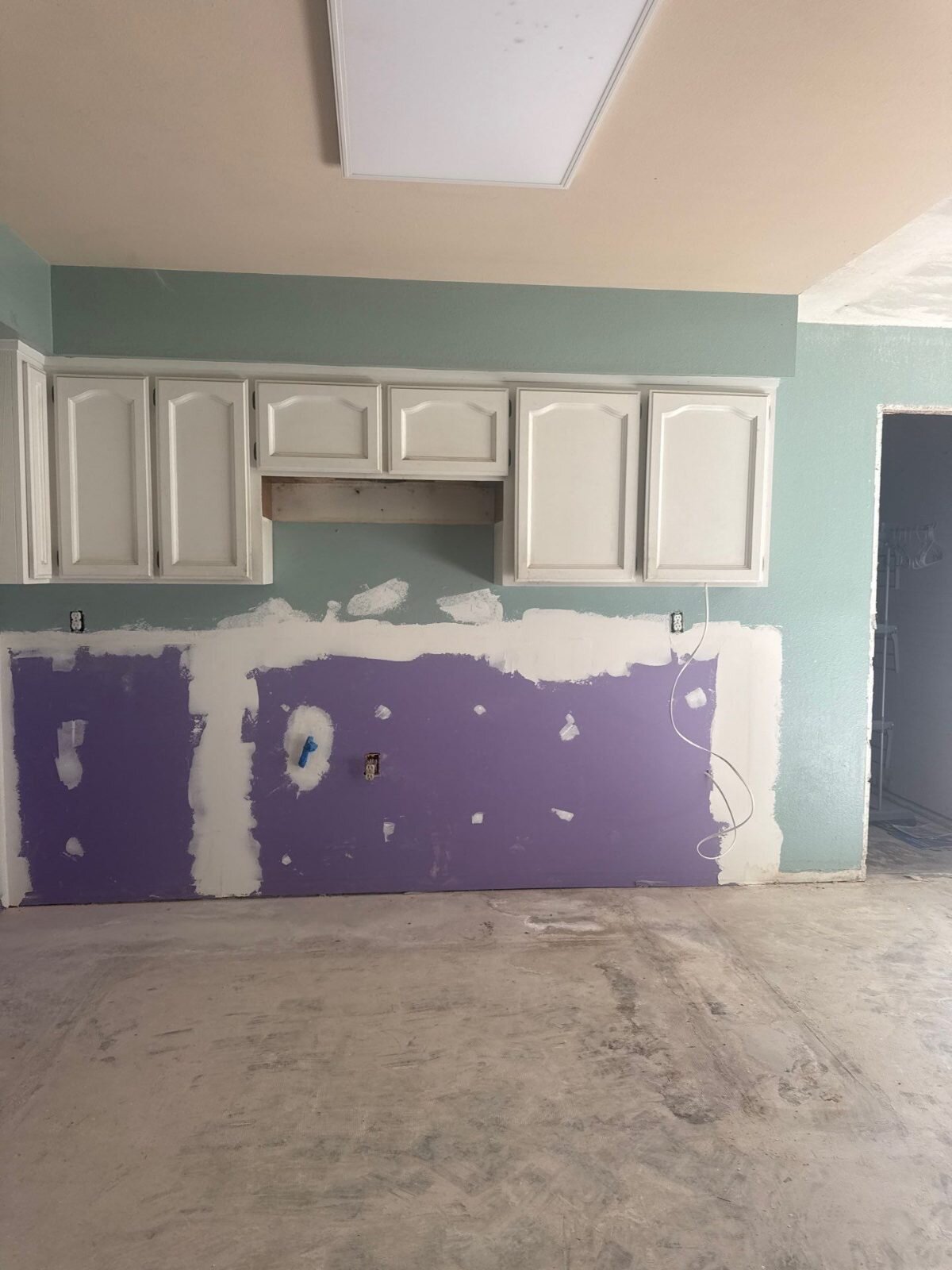 Gutted kitchen with patched drywall in a vacant Clovis house sold as-is