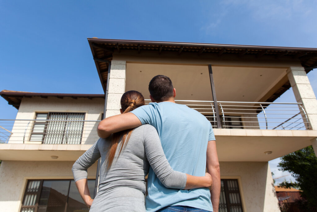 Couple with their arms around each other looking at a house