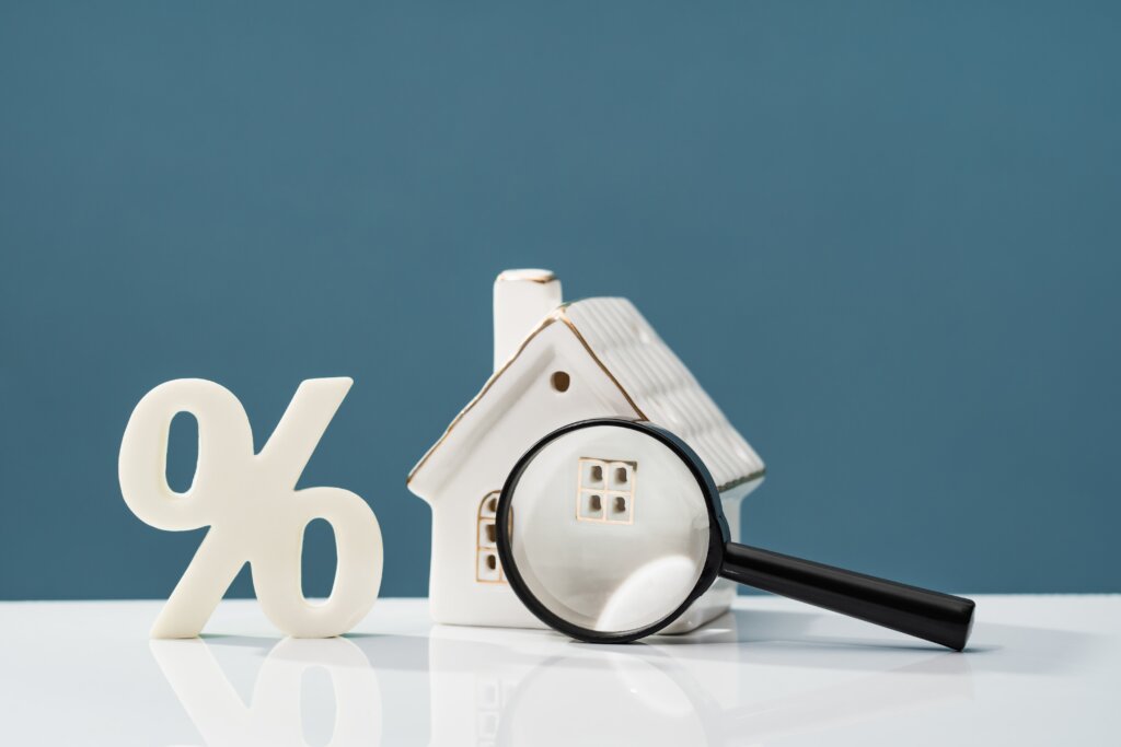 Percent sign, small house model and a magnifying glass