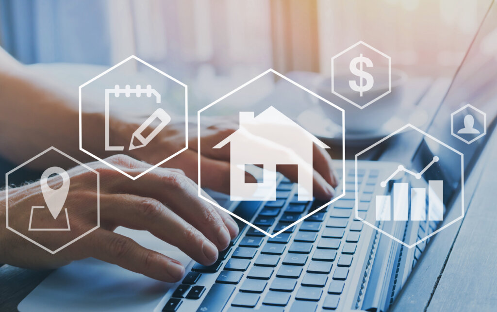 Hands typing on a laptop with real estate icons above the keyboard