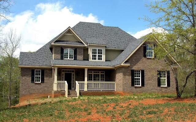 Two-story brick house with a front porch and a bare dirt yard