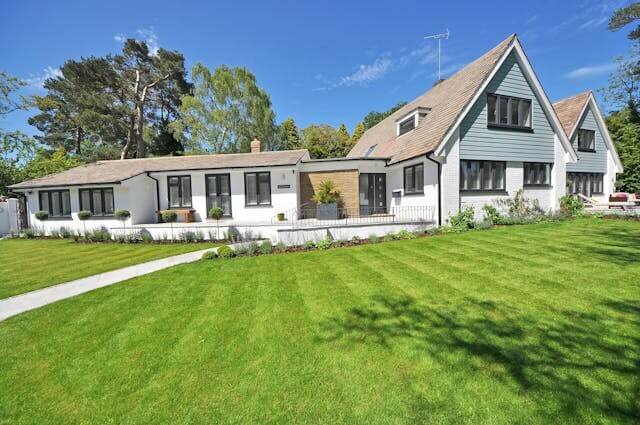 White farmhouse-style house with a wide green lawn