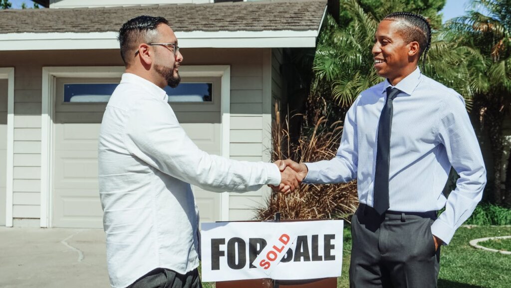 Men shaking hands outside of a house