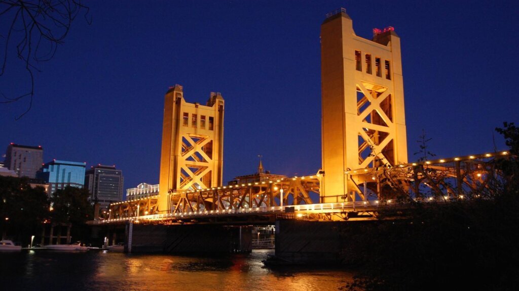 Sacramento's Tower Bridge lit up at night over the Sacramento River