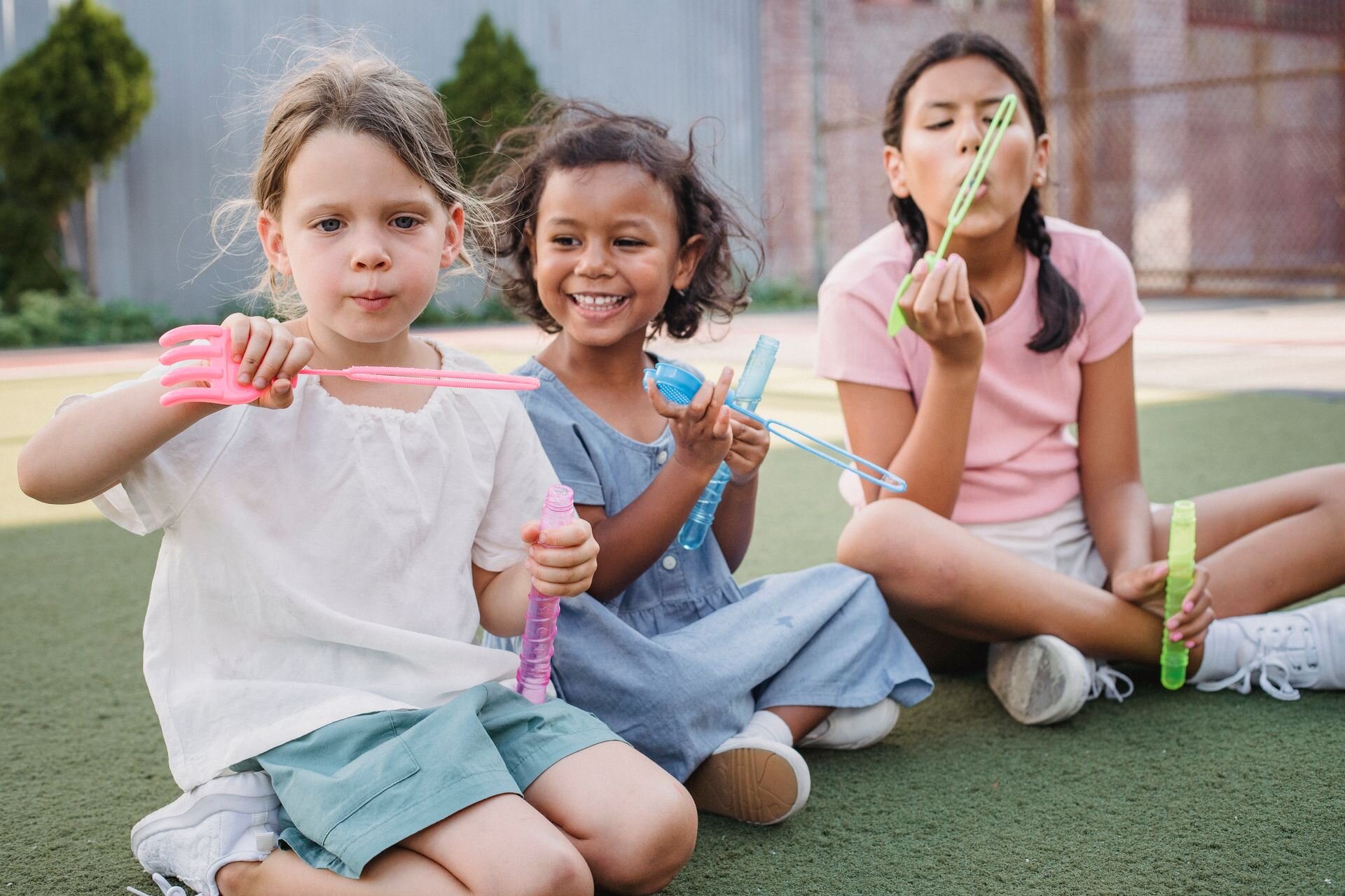 Children sitting and blowing bubbles outside